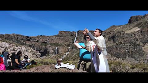 Un sacerdote realiza un ritual al aire libre frente a un hermoso paisaje montañoso.
