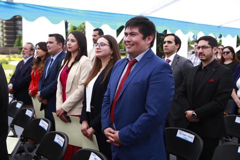 Un grupo de personas vestidas formalmente asisten a un evento al aire libre.