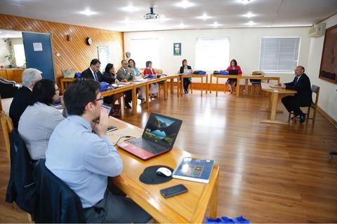 Una reunión en una sala con varias personas sentadas alrededor de una mesa.