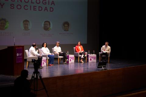 Un panel de discusión sobre tecnología y sociedad en un auditorio.