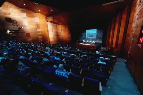 Una gran multitud está sentada en un auditorio durante un evento.