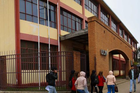 Un grupo de estudiantes se dirige hacia un edificio educativo en un día nublado.