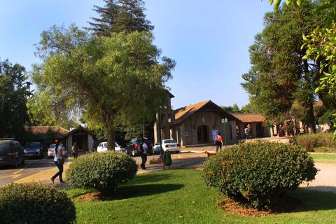 Una vista de un parque con senderos, árboles y construcciones de piedra al fondo.