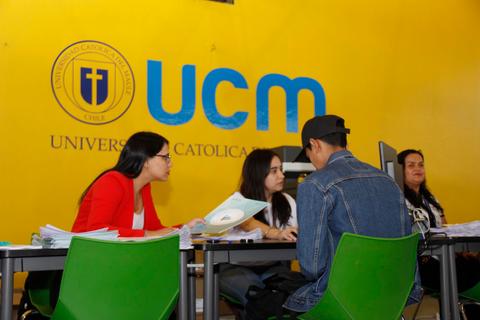 Un grupo de estudiantes interactúa en una oficina de atención en la Universidad Católica de Chile.
