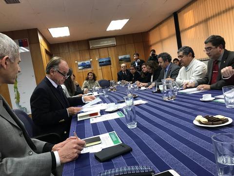 Reunión de varias personas alrededor de una mesa de conferencias en un ambiente formal.