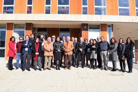 Un grupo de personas posando frente a un edificio moderno en un día soleado.