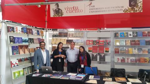Un grupo de cuatro personas posando en un stand de libros en una feria.