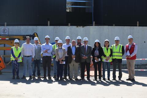 Un grupo de personas posando en un sitio de construcción, todos vistiendo cascos y chalecos de seguridad.