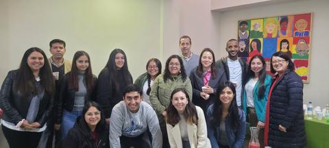 Un grupo de personas sonrientes posando juntas en una sala con decoraciones coloridas.