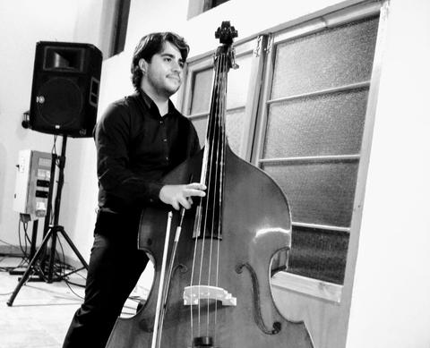 Un joven músico toca un contrabajo en una sala de música.