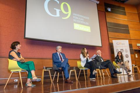 Un panel de discusión con cinco personas sentadas en un escenario, con un fondo que incluye el logotipo G9 y el texto 'Universidades Públicas No Estatales'.