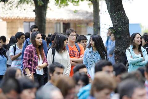 Un grupo de jóvenes conversando y caminando al aire libre en un entorno universitario.