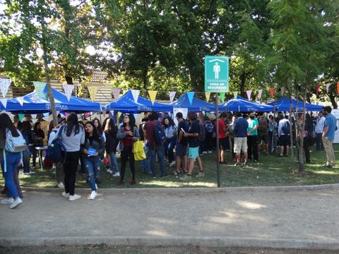 Una multitud de personas en un evento al aire libre rodeado de carpas y banderas.