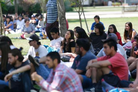 Un grupo de jóvenes sentados en un espacio al aire libre, disfrutando de una actividad juntos.
