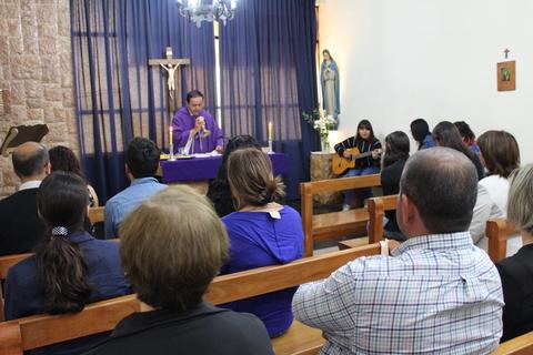 Un grupo de personas asiste a una ceremonia religiosa en una pequeña capilla.