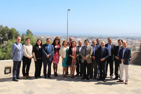 Un grupo de personas posando juntas con un paisaje urbano de fondo en un día soleado.