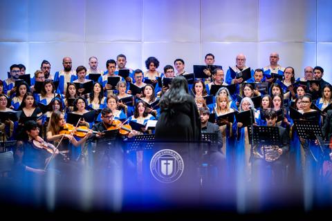 Un gran coro con músicos tocando instrumentos en un escenario iluminado.