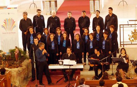 Un grupo de cantantes de coro se presenta sobre un escenario en una iglesia, con un pianista y guitarristas.