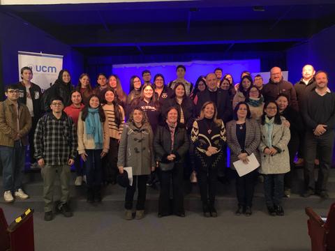 Un grupo de personas posando juntas en un escenario iluminado con tonos azules.