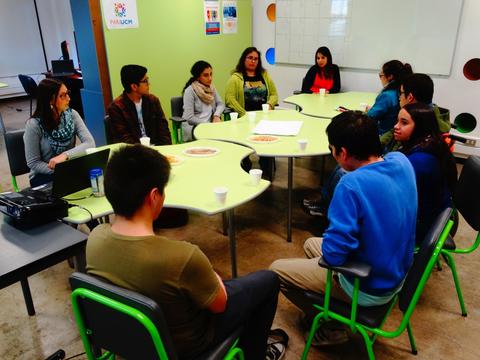Un grupo de jóvenes se reúne alrededor de una mesa en un ambiente de trabajo colaborativo.