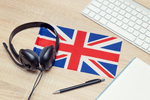 Una mesa con auriculares, un bolígrafo y una bandera del Reino Unido.