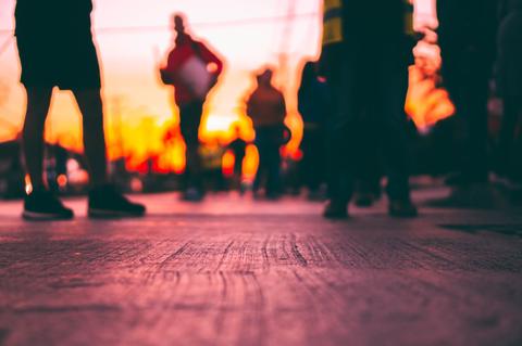 La imagen muestra siluetas de personas en un atardecer con un ambiente urbano.