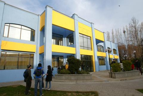 Una edificación moderna de color azul con detalles amarillos y personas en su exterior.
