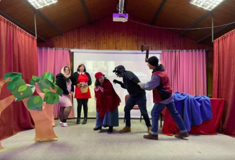 Un grupo de personas disfrazadas representando una escena de un cuento en un escenario decorado.