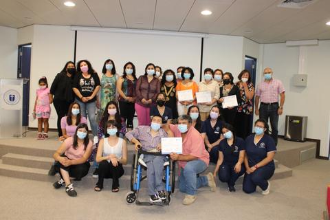 Un grupo de personas posando con certificados en un evento, todos usando mascarillas.