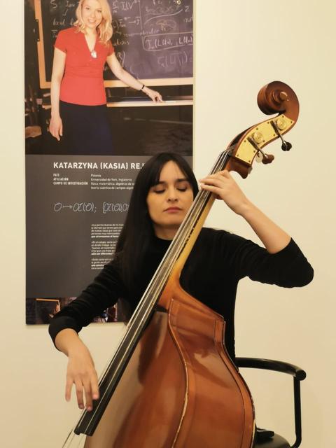Una mujer está tocando un contrabajo en un ambiente artístico.
