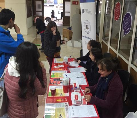Un grupo de personas interactúa en un stand informativo en un evento.