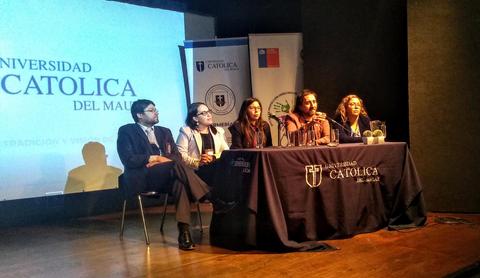 Un grupo de personas sentadas detrás de un escritorio en un evento de la Universidad Católica del Maule.