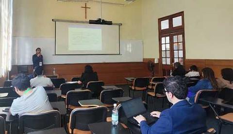 Una presentación en un aula universitaria con una ponente y varios asistentes.