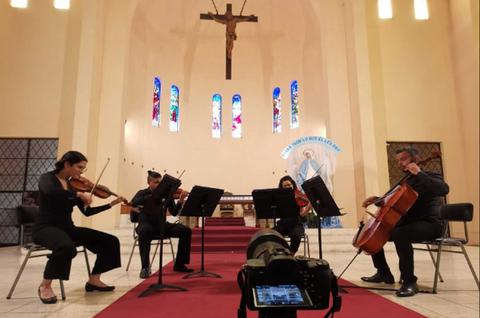Un cuarteto de músicos toca en un ambiente religioso dentro de una iglesia.