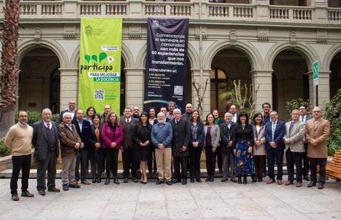 Un grupo de personas posando en un evento en un bonito recinto con pancartas de participación y comunidad en el fondo.