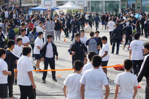 Un grupo de estudiantes participando en actividades deportivas al aire libre en una cancha.