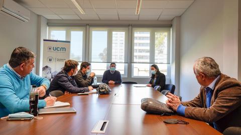 Un grupo de personas en una reunión en una oficina, todos usando mascarillas.