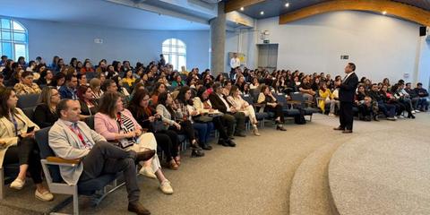 Una gran multitud de personas asiste a una conferencia en un auditorio.