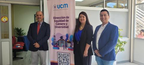 Tres personas posan frente a un cartel de la Dirección de Equidad de Género y Diversidad de la UCM.