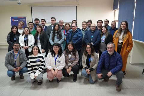 Un grupo de personas posando en un ambiente de oficina, todos luciendo sonrientes y con tarjetas de identificación.