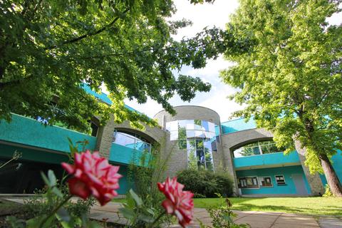 Una vista de un edificio moderno rodeado de árboles y flores.