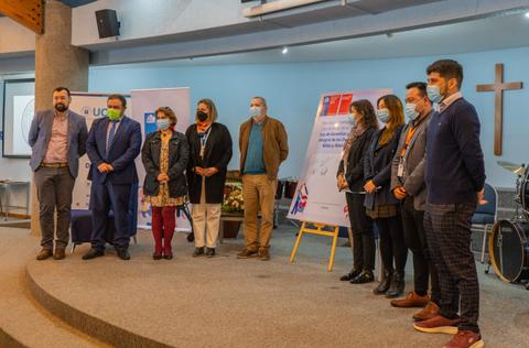 Un grupo de personas posando en un evento formal con presentaciones en un escenario.
