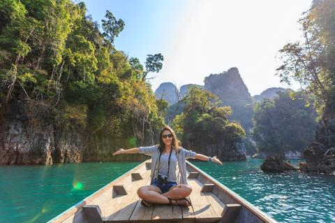 Una mujer sonriente disfruta de un paseo en bote en un hermoso paisaje natural.