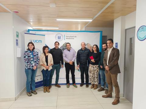 Grupo de personas posando frente a un banner de la Facultad de Medicina.