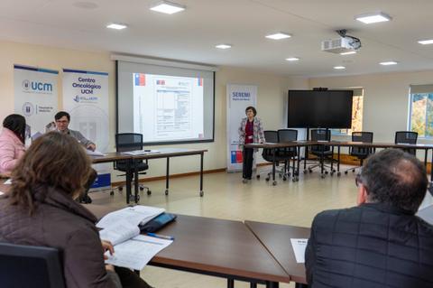 Una reunión en una sala con una presentación en pantalla sobre temas relacionados con la salud.