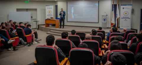 Un expositor presenta un tema frente a una audiencia en un salón de clases en Chile.