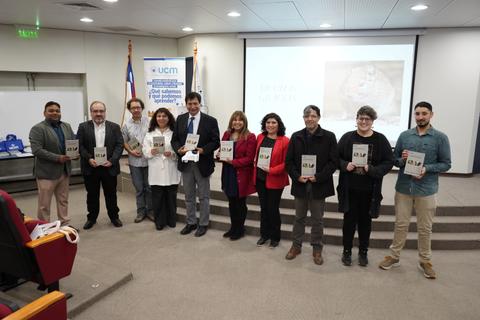 Una presentación de libro con varias personas sosteniendo ejemplares en un auditorio.
