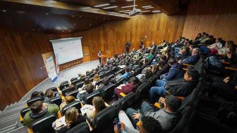 Una charla con un gran número de asistentes en un auditorio moderno.