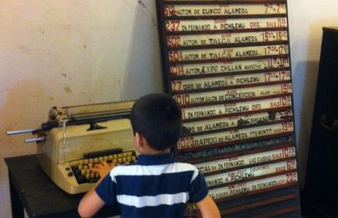 Un niño está frente a una máquina de escribir antigua en un entorno que muestra objetos vintage.