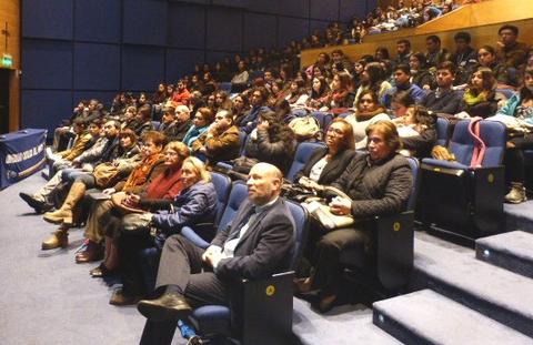Una gran audiencia se reúne en un auditorio frente a un escenario.